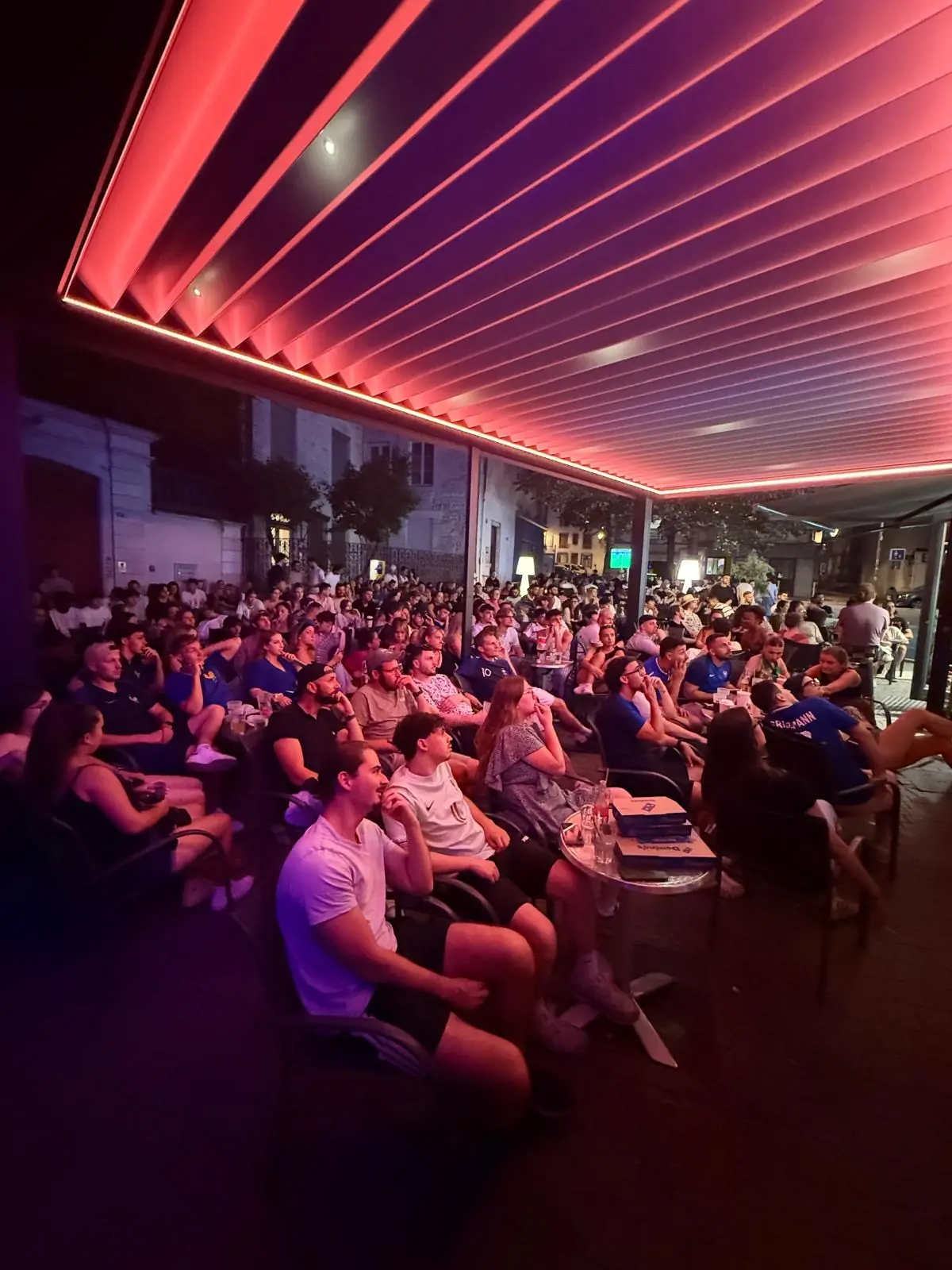 Public installé sous la pergola rouge du K32 Factory pendant une soirée