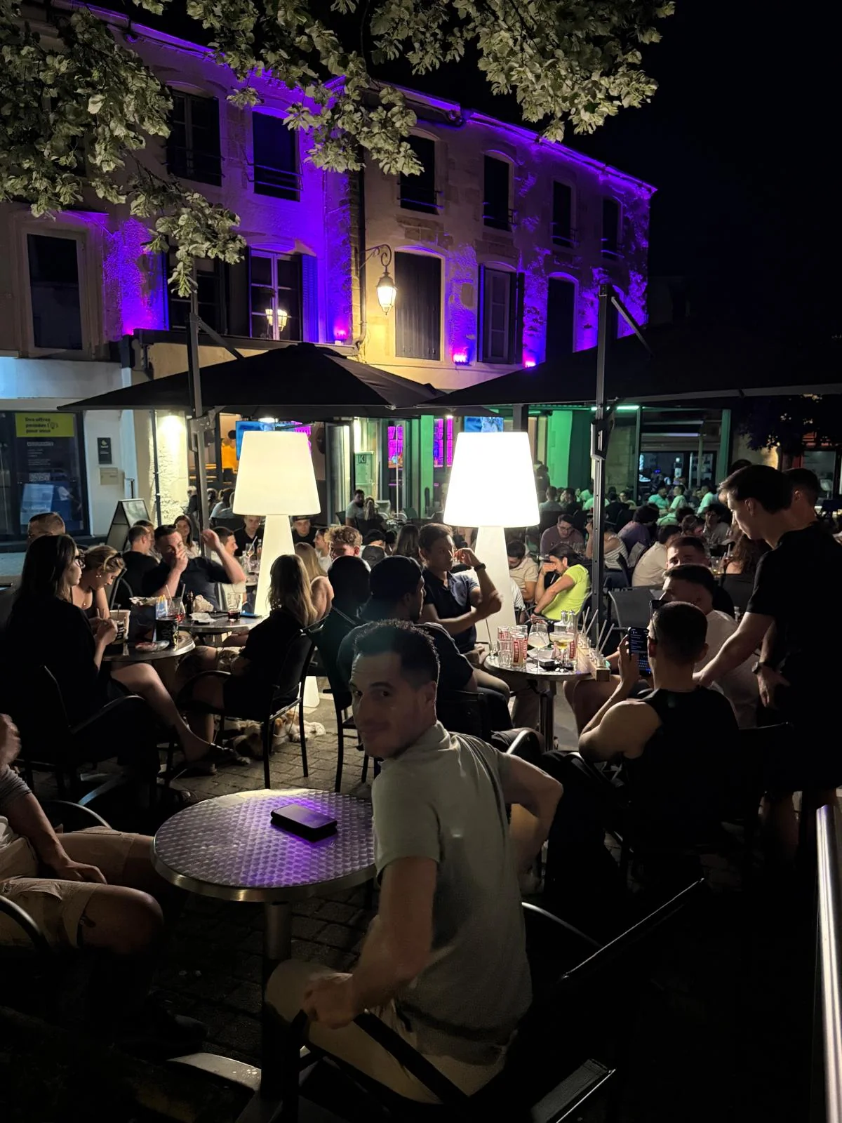 Terrasse animée et façade violette du K32 Factory pendant une soirée à Chaumont